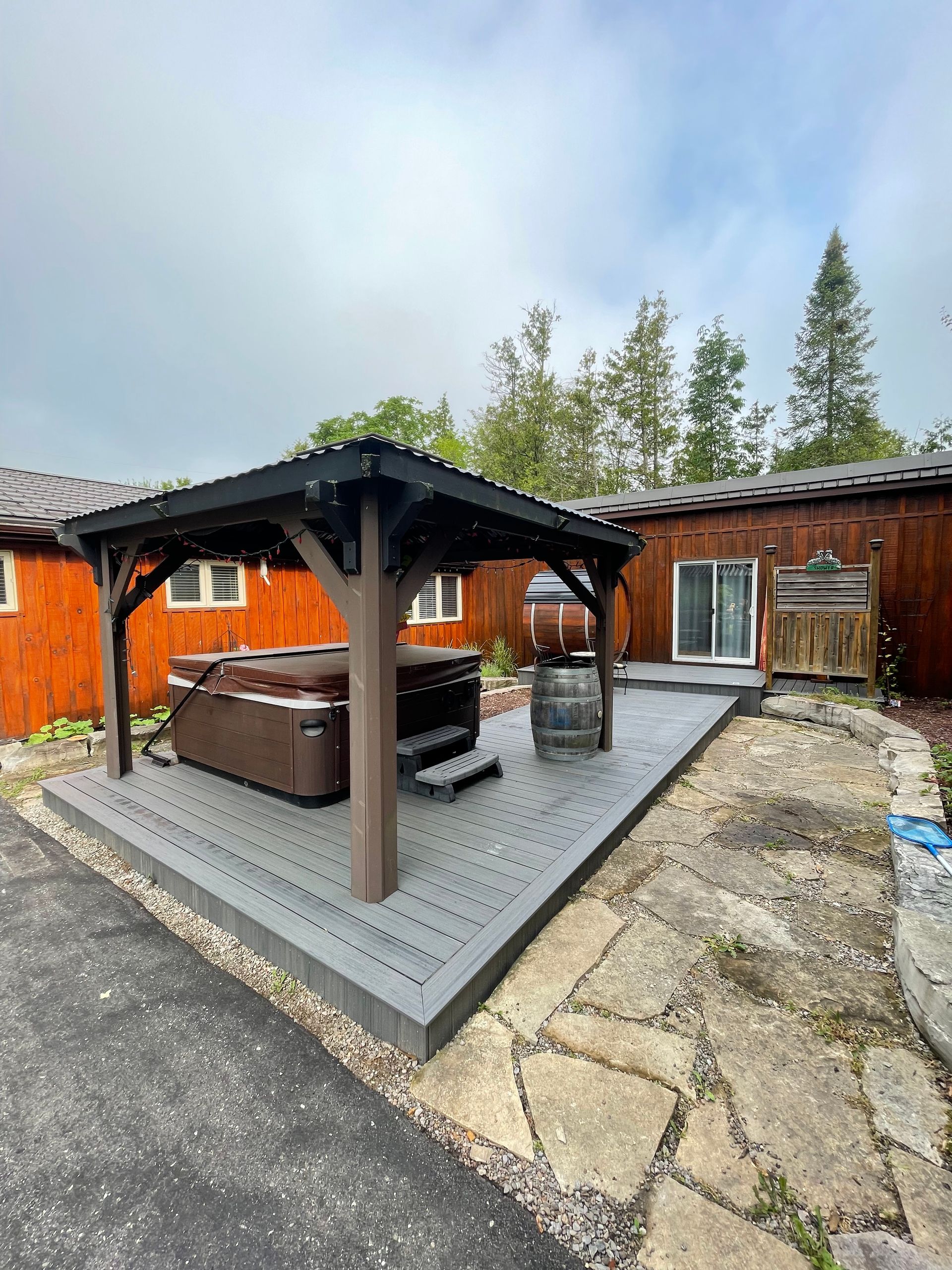 A gazebo with a hot tub underneath it in front of a house.