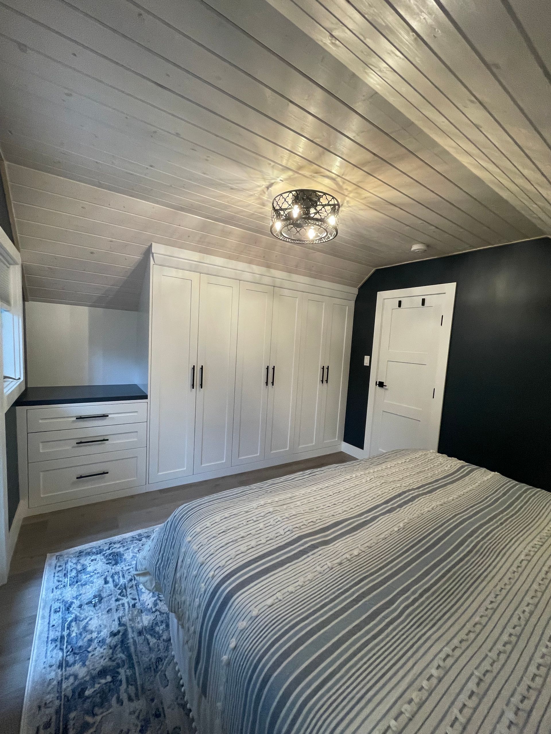 A bedroom with a bed , dressers , and a chandelier.