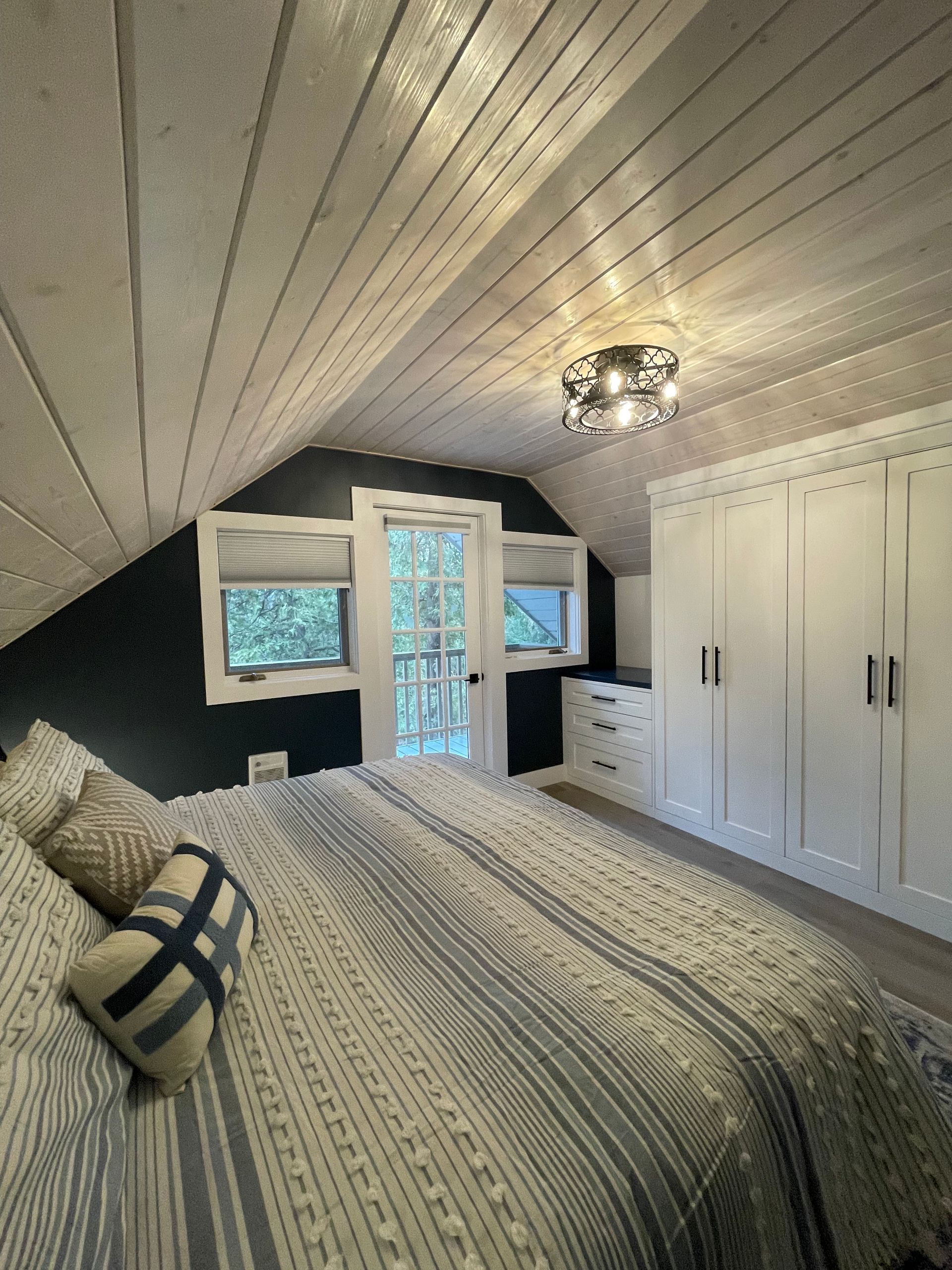 A bedroom with a king size bed , closets , and a balcony.