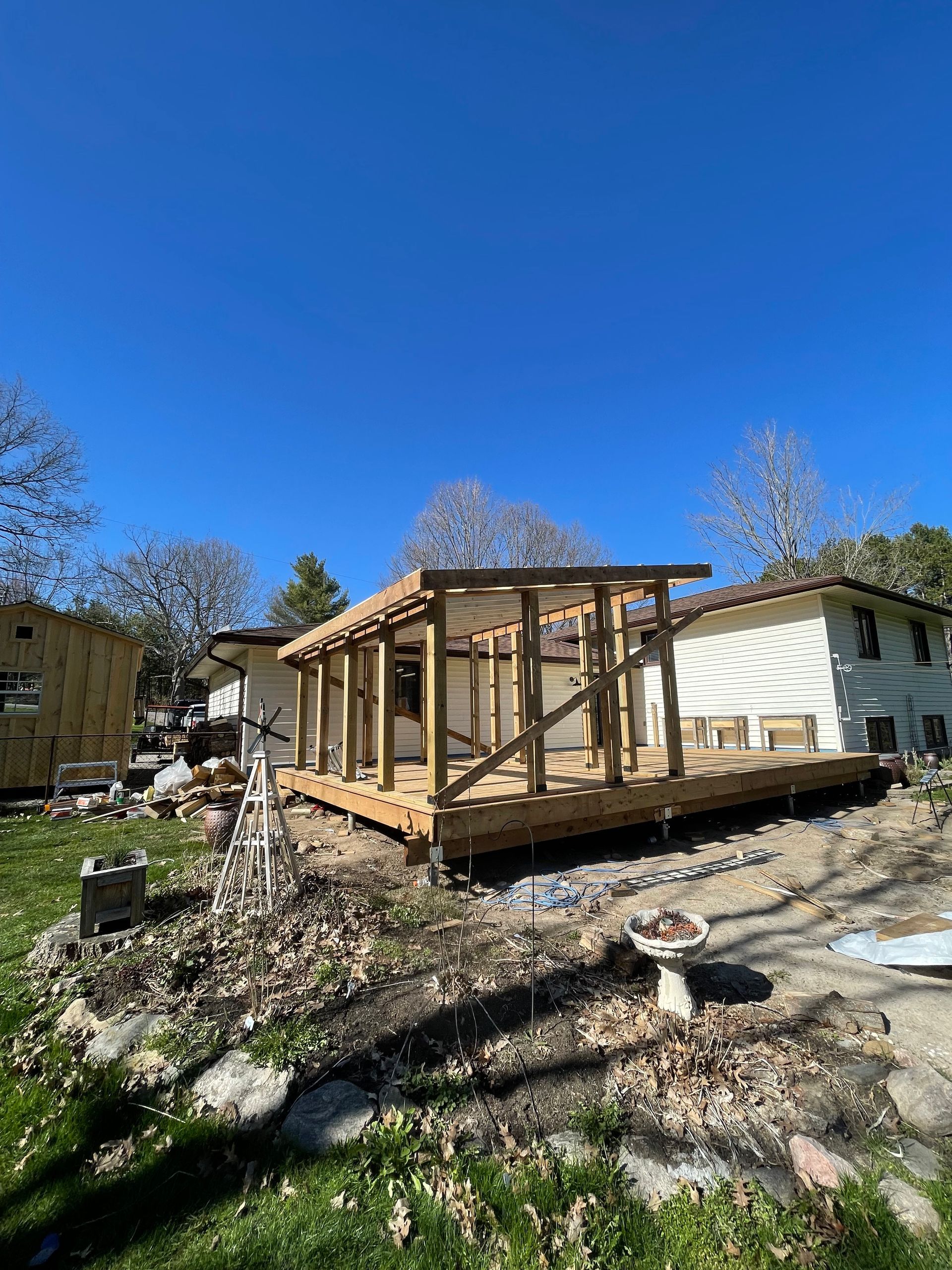 A wooden structure is being built in the backyard of a house.