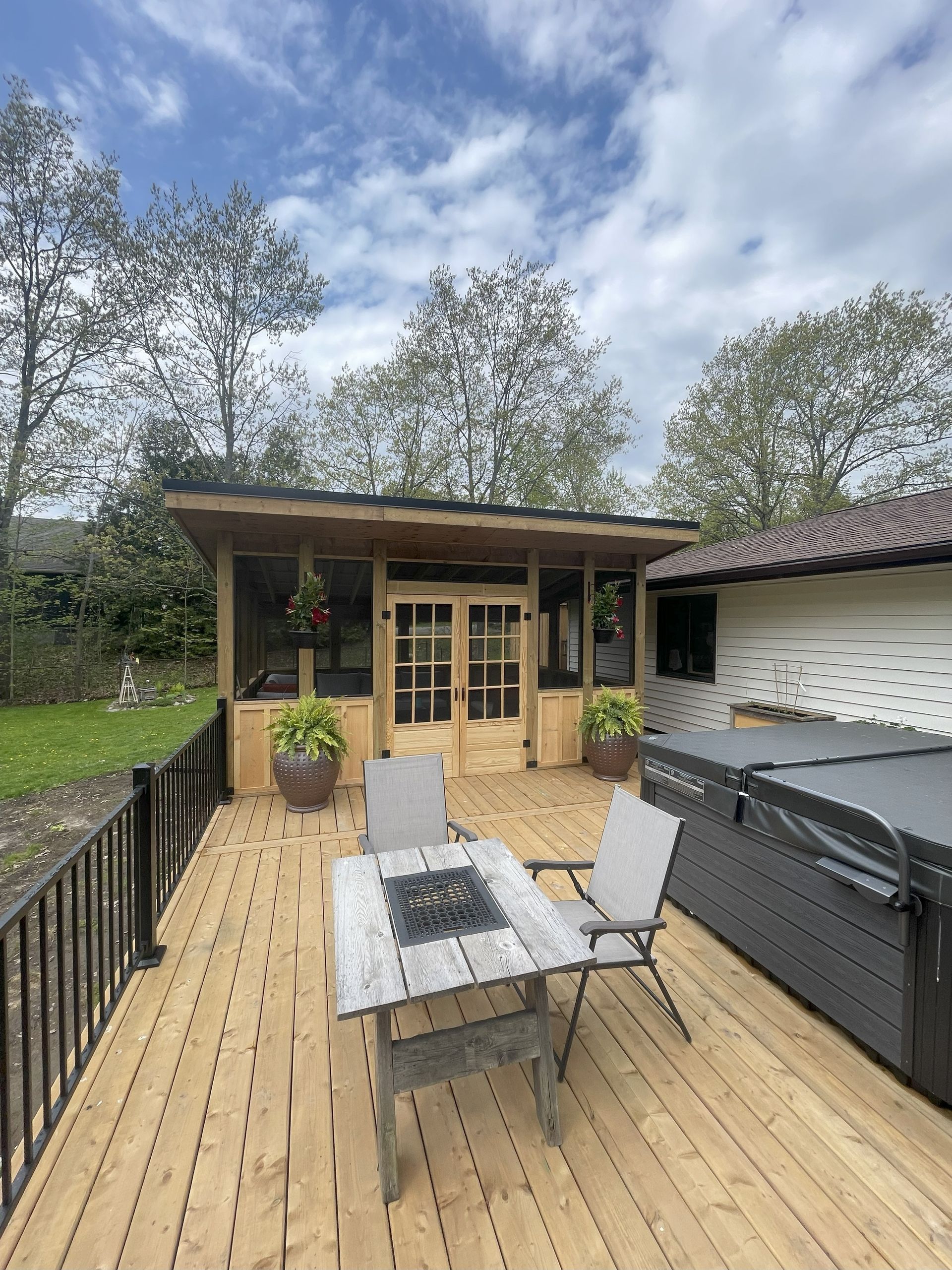 A wooden deck with a table and chairs and a hot tub.
