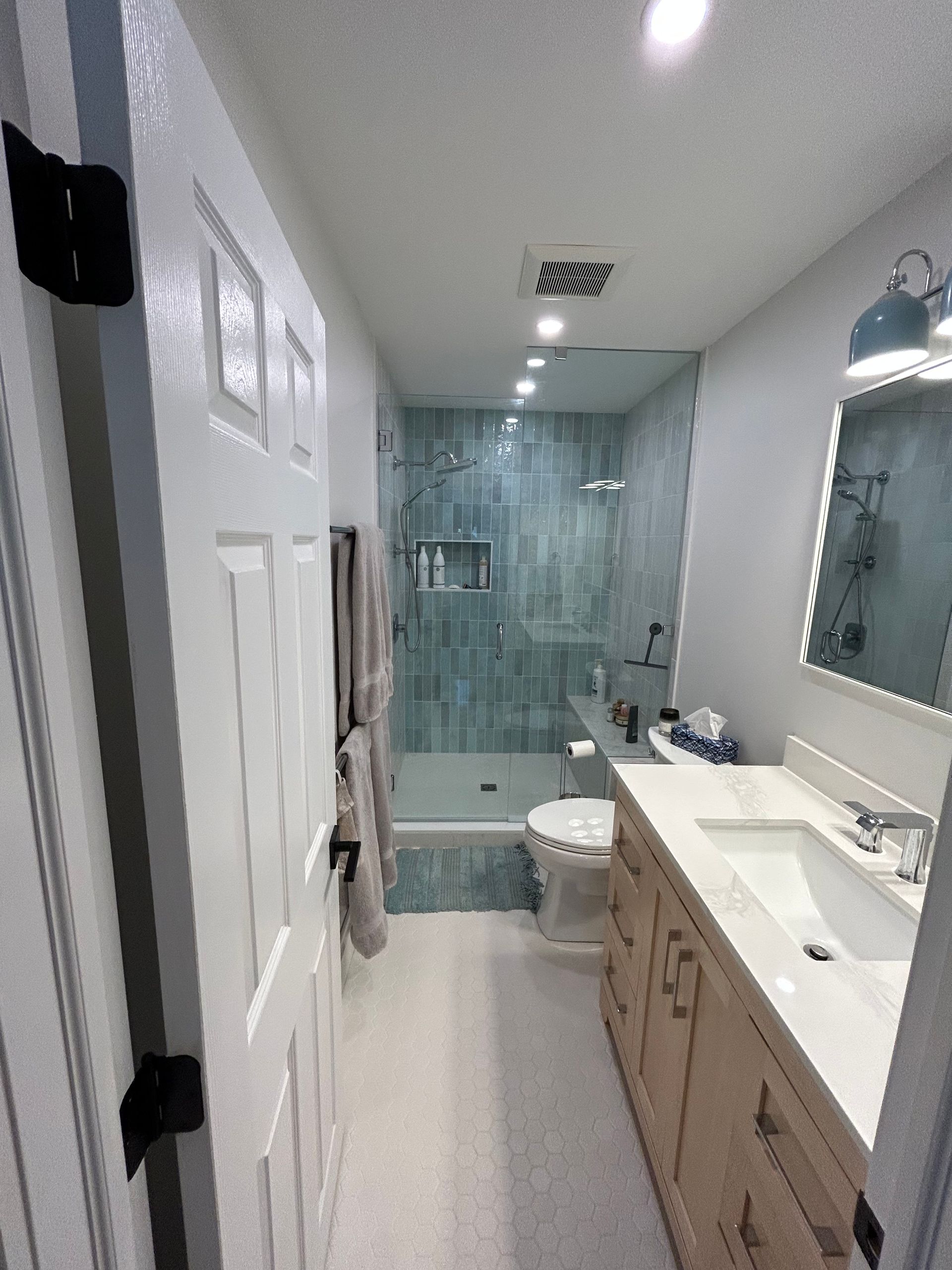 A bathroom with a sink , toilet , shower and mirror.