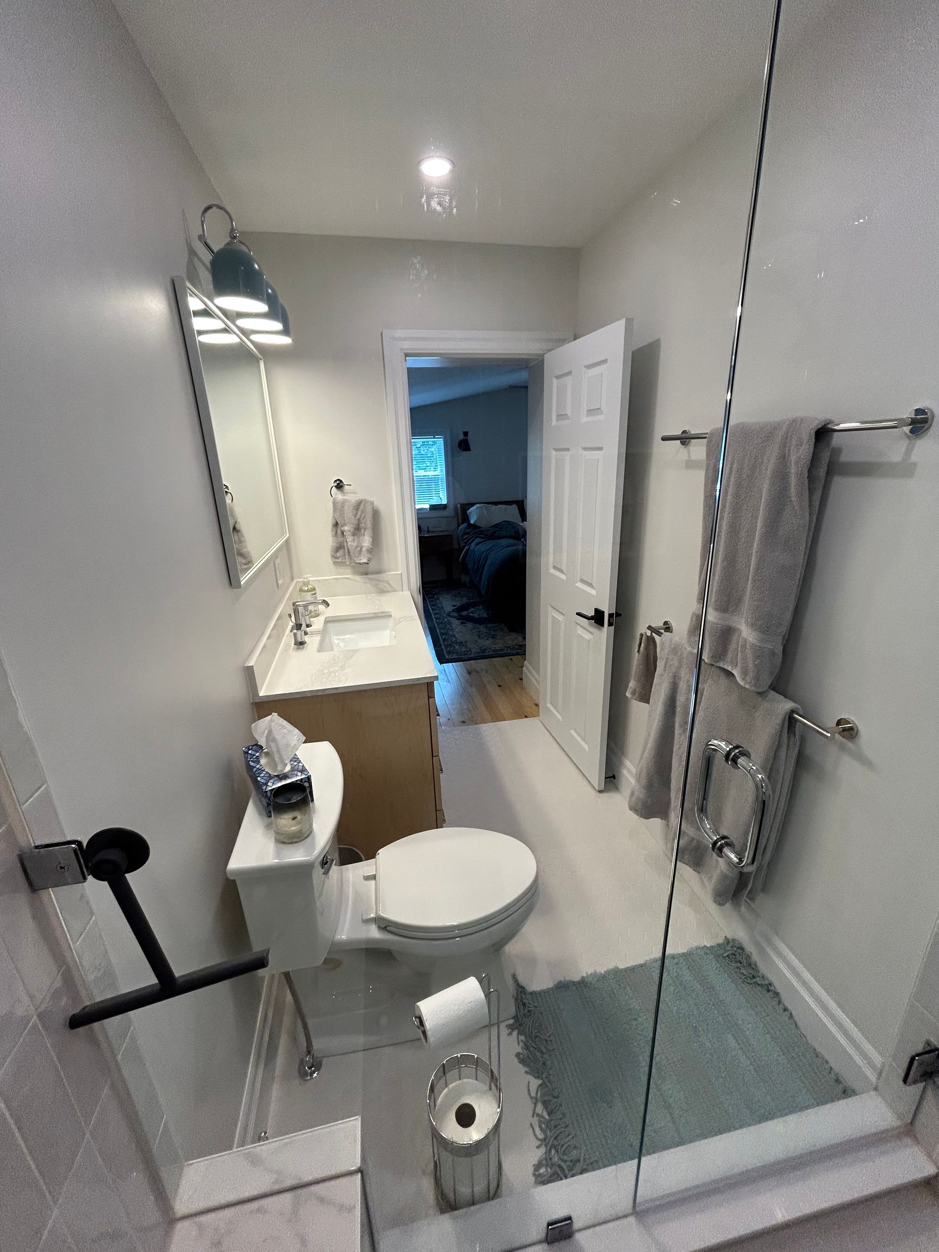 A bathroom with a toilet , sink , mirror and walk in shower.