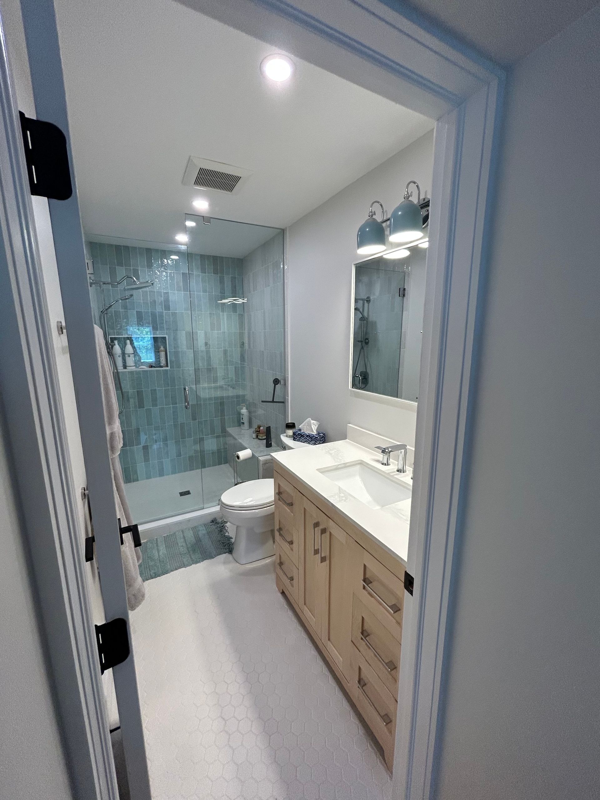 A bathroom with a toilet , sink , mirror and shower.
