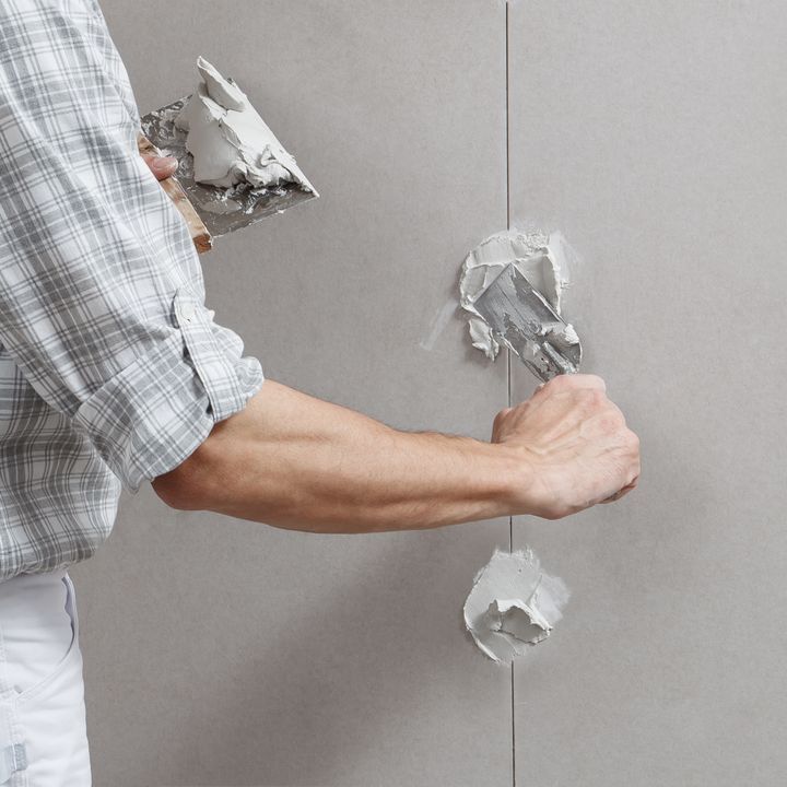 A man is plastering a wall with a spatula