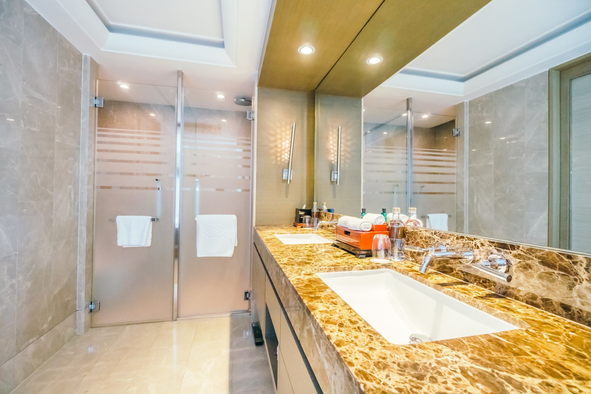 Modern bathroom with marble vanity, large mirror, and frosted glass shower doors