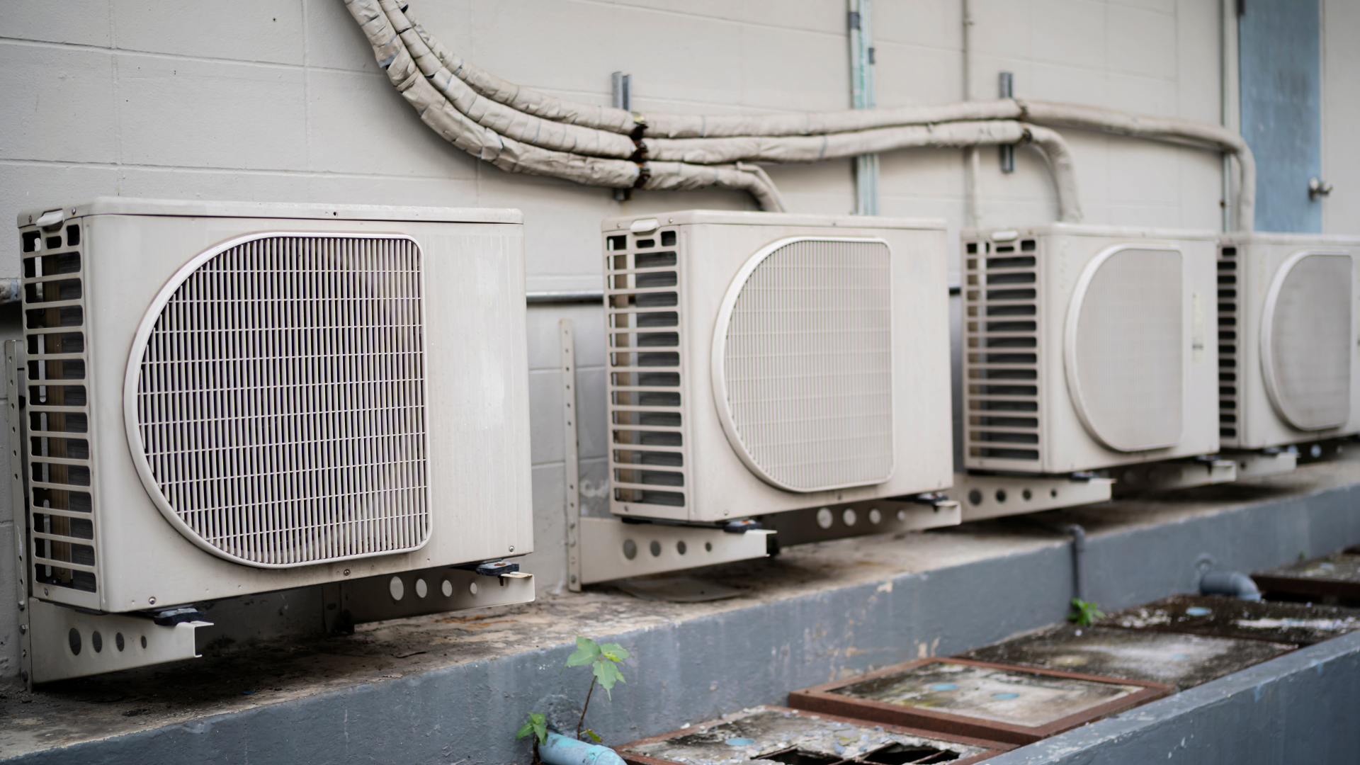A row of air conditioners are sitting on the side of a building.