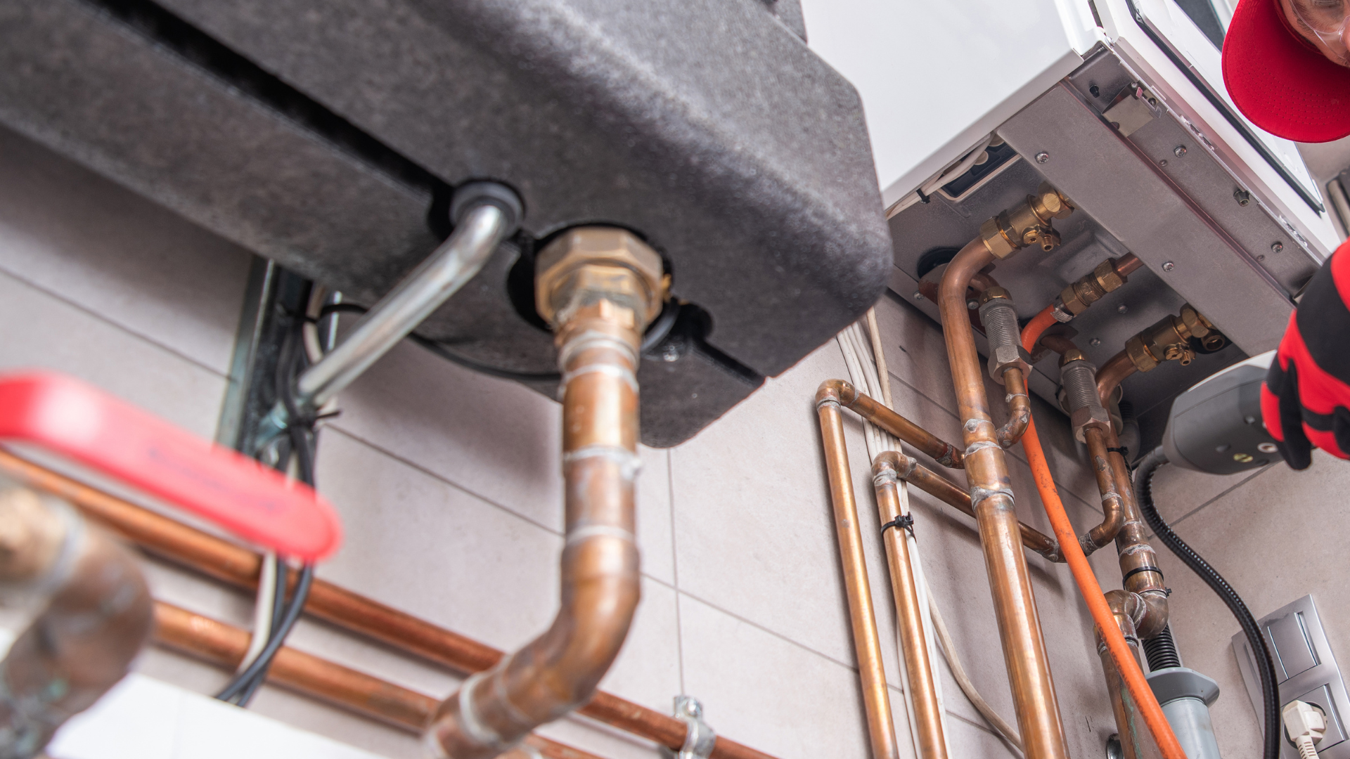A plumber is working on a boiler in a bathroom.
