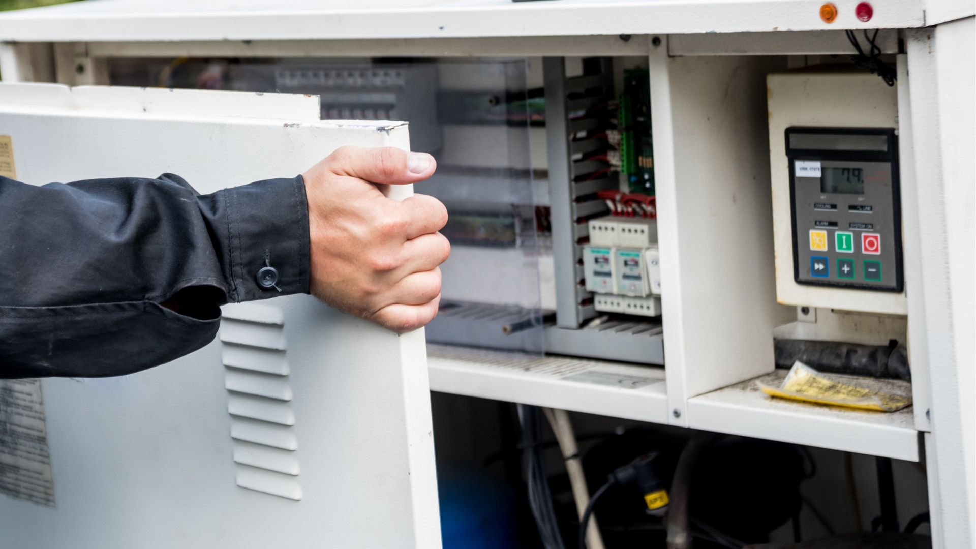 A man is opening the door of an electrical box.