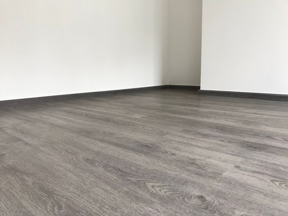 Empty room with gray wood-look flooring and white walls. — Ozwide Flooring In Ciccone, NT
