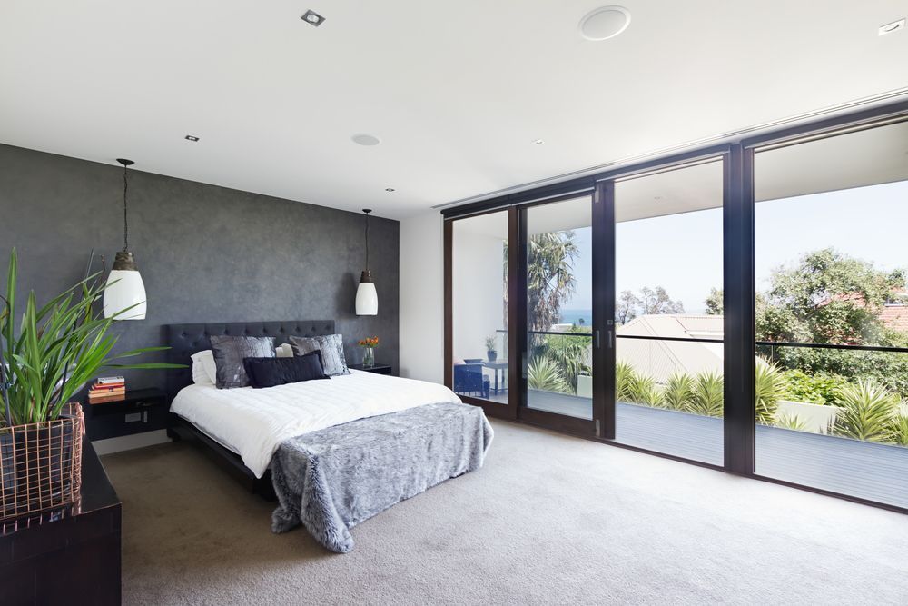 Bedroom with gray walls, bed, and large glass doors leading to a balcony. — Ozwide Flooring In Ciccone, NT