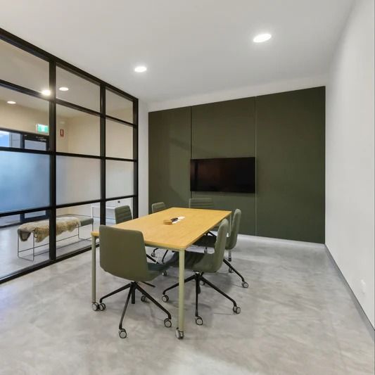 Conference room with table, chairs, TV, and frosted glass wall. Green accent wall and light concrete floor. — Ozwide Flooring In Ciccone, NT