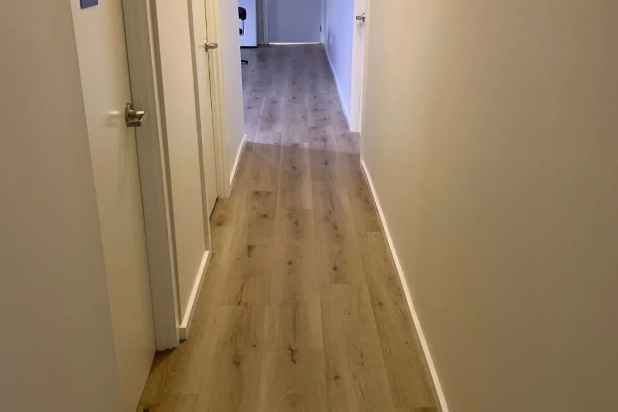 Narrow Hallway With Light-coloured Wood-look Flooring and White Walls — Ozwide Flooring In Ciccone, NT