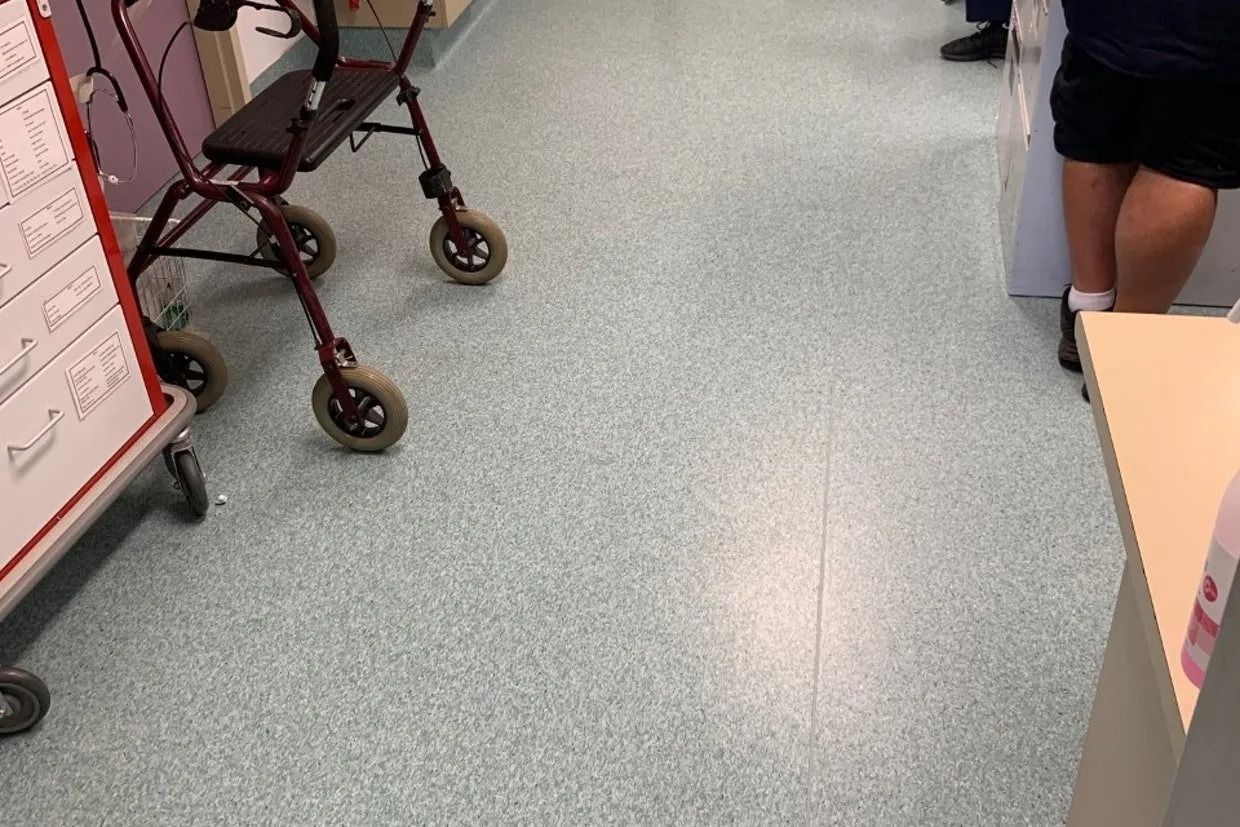 A Hospital Hallway With a Walker and a Person Standing Near a Counter — Ozwide Flooring In Ciccone, NT