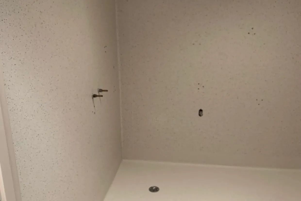 Corner of a White-walled Shower With Fixture Holes and Drain — Ozwide Flooring In Ciccone, NT