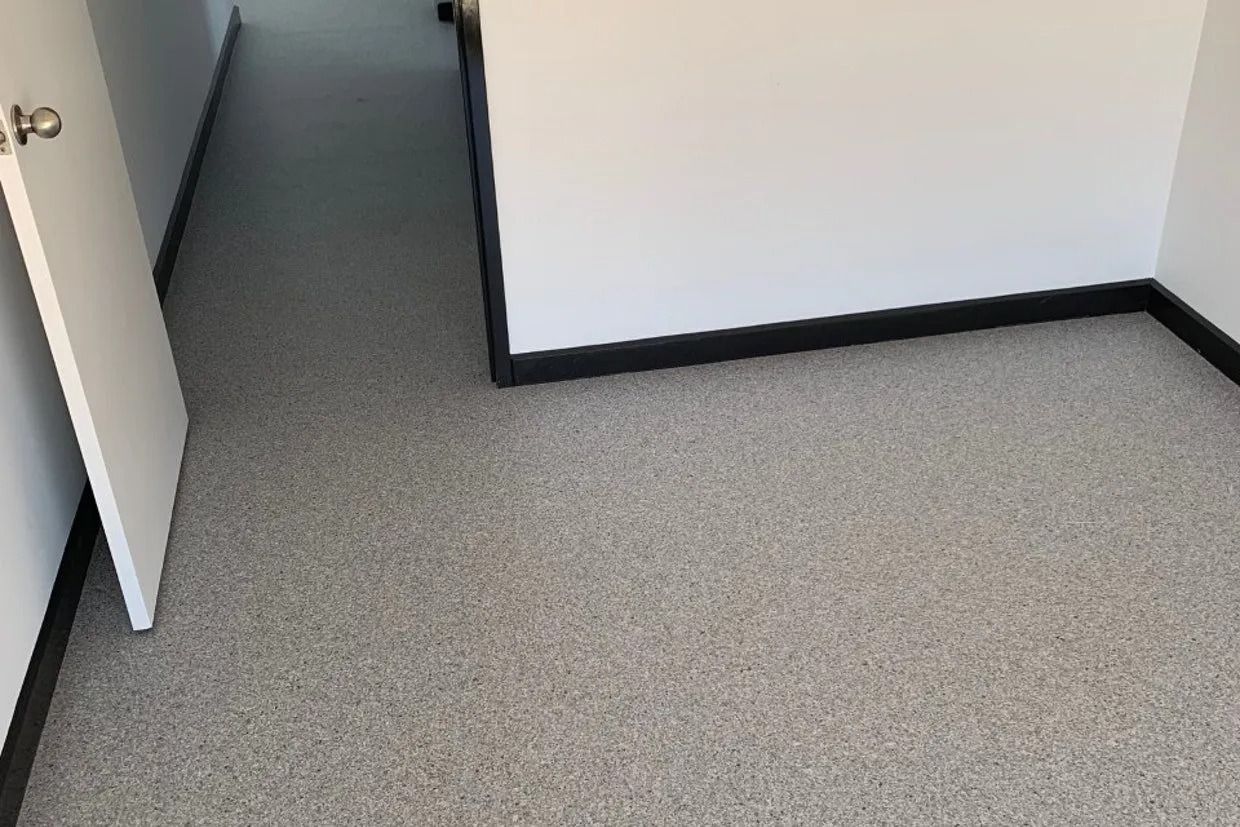 Grey Speckled Flooring With White Walls and Black Baseboards; Doorway on the Left — Ozwide Flooring In Ciccone, NT