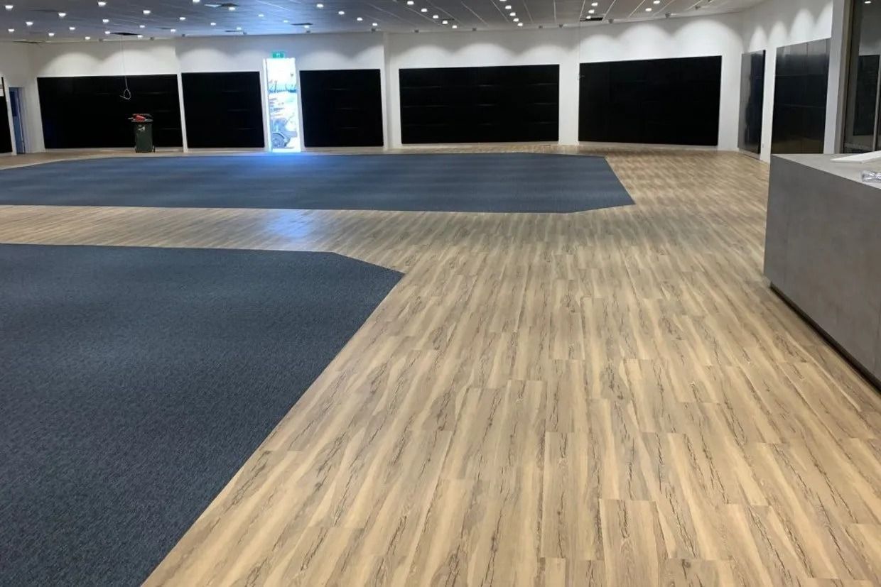 Large Empty Room With Wood and Blue Carpet Flooring — Ozwide Flooring In Ciccone, NT