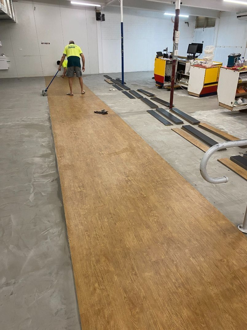 Person Applying Flooring in a Warehouse — Ozwide Flooring In Ciccone, NT
