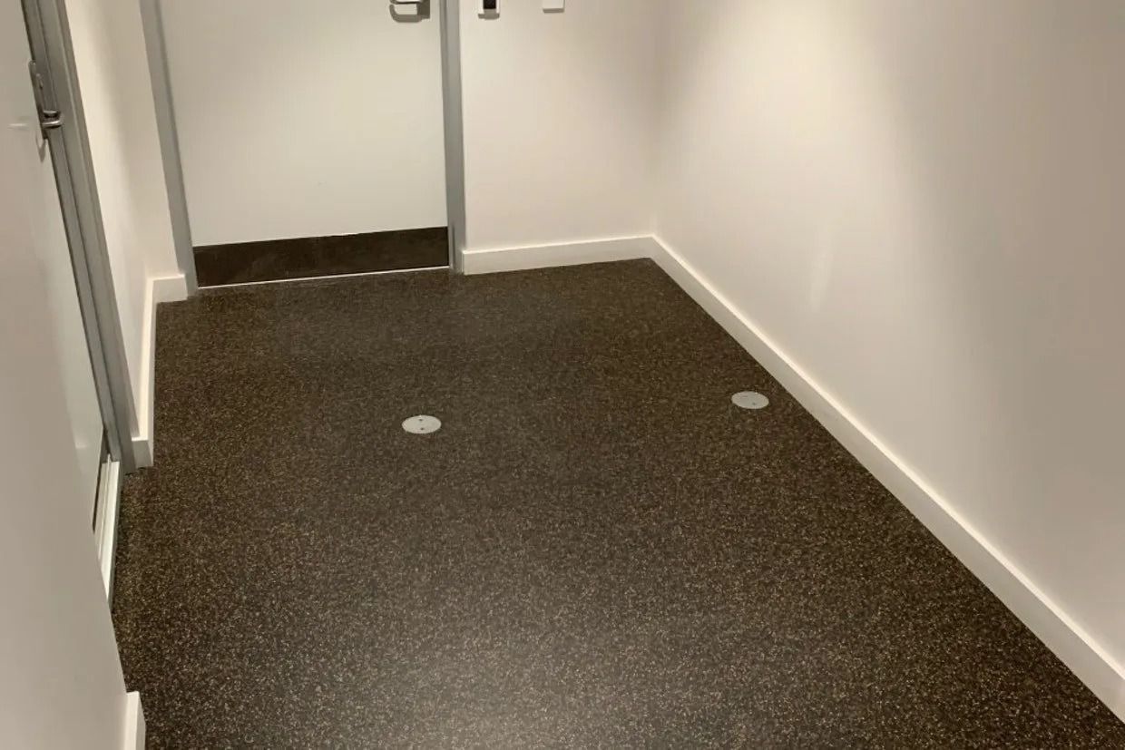 Narrow Hallway With Dark Speckled Flooring, White Walls, and a Closed Door — Ozwide Flooring In Ciccone, NT