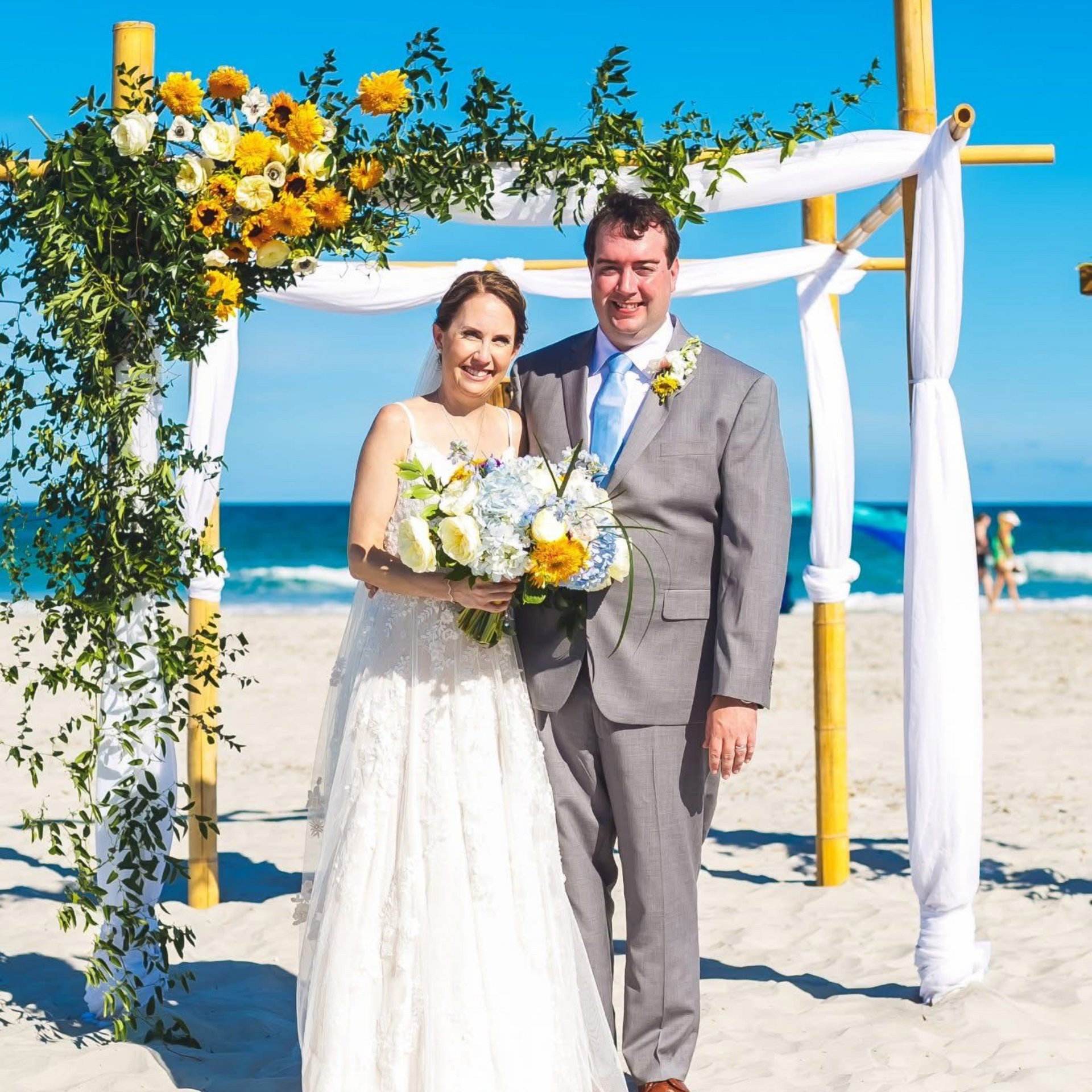 Woman with curly hair in pink sweater smiles while sitting on a couch.