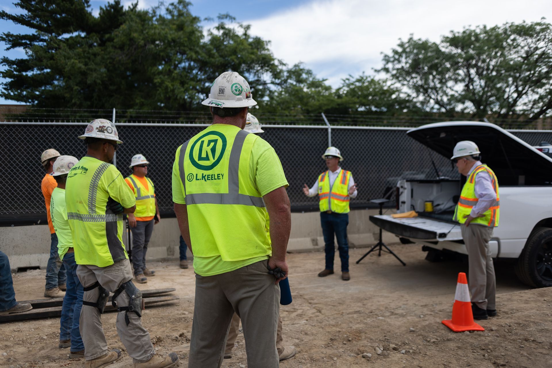 A group of construction workers are standing in front of a truck.