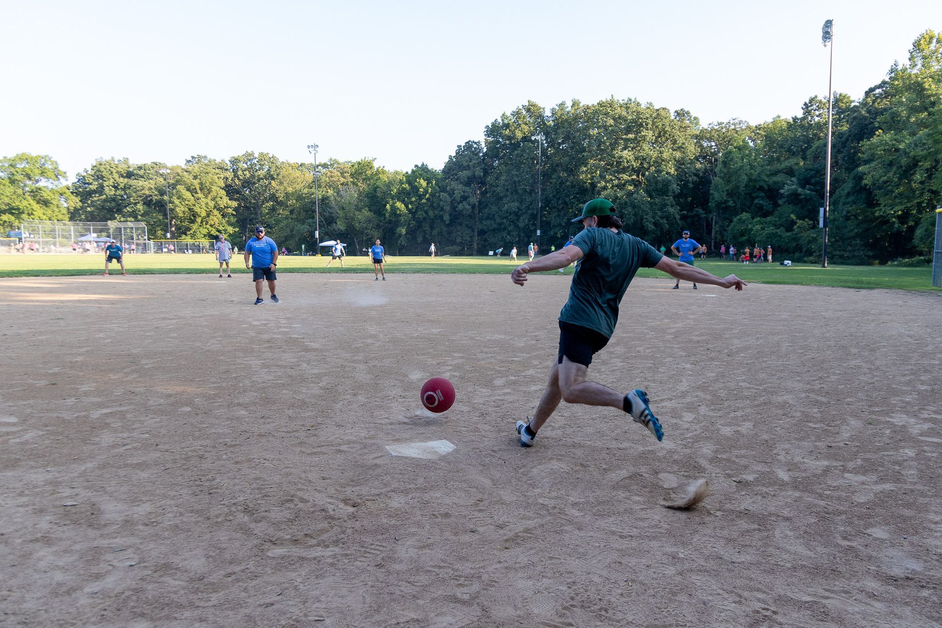 A man is kicking a soccer ball on a dirt field.