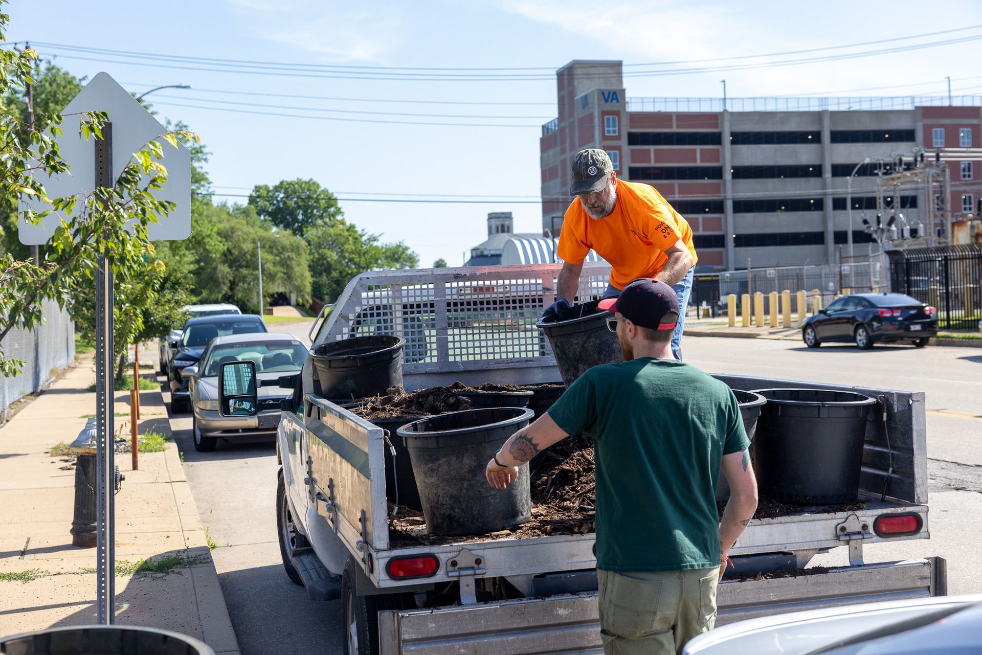 Two men are loading buckets into the back of a truck.
