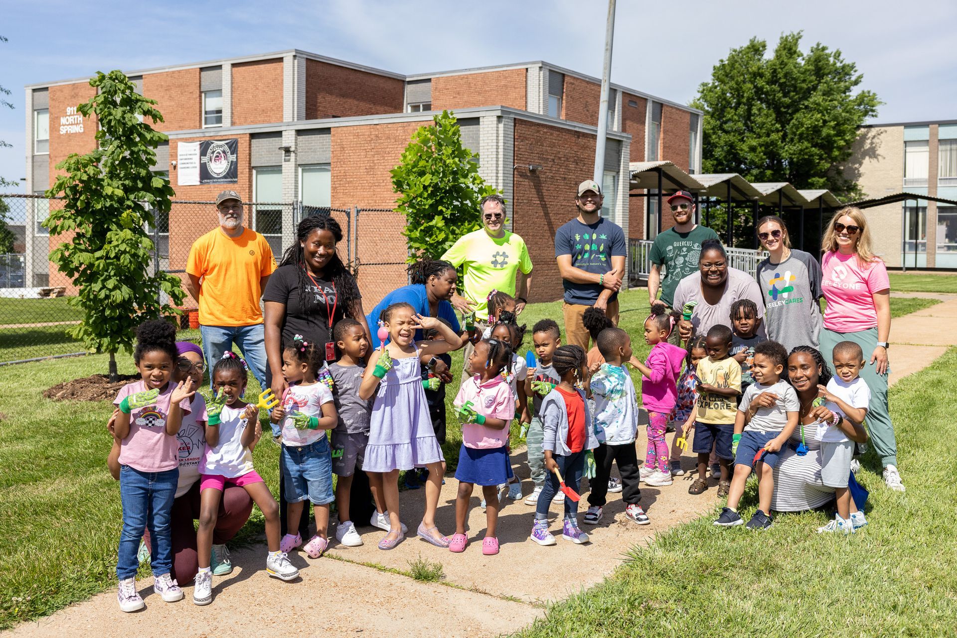 A group of children and adults are posing for a picture in front of a building.