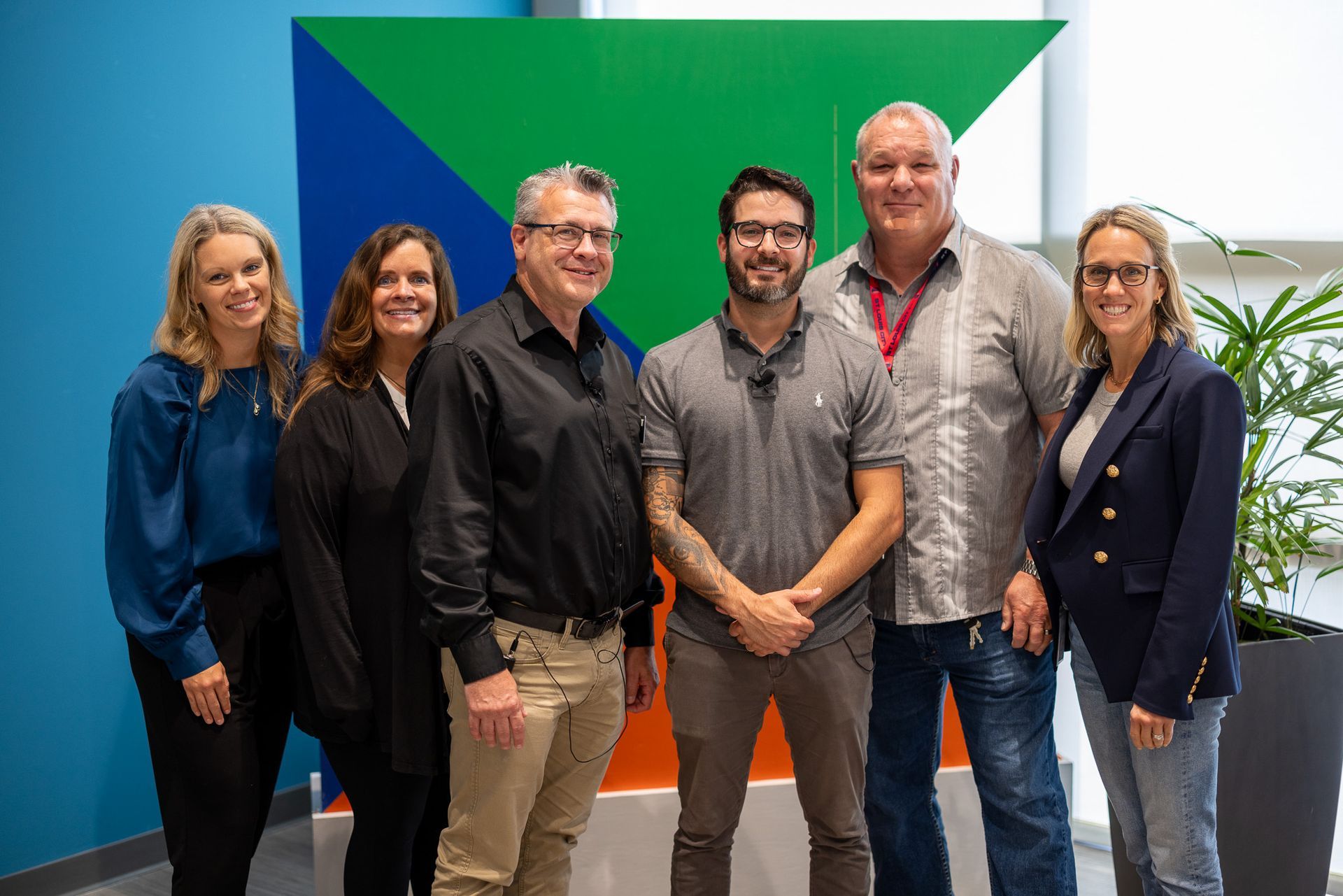 A group of people are posing for a picture in front of a colorful wall.