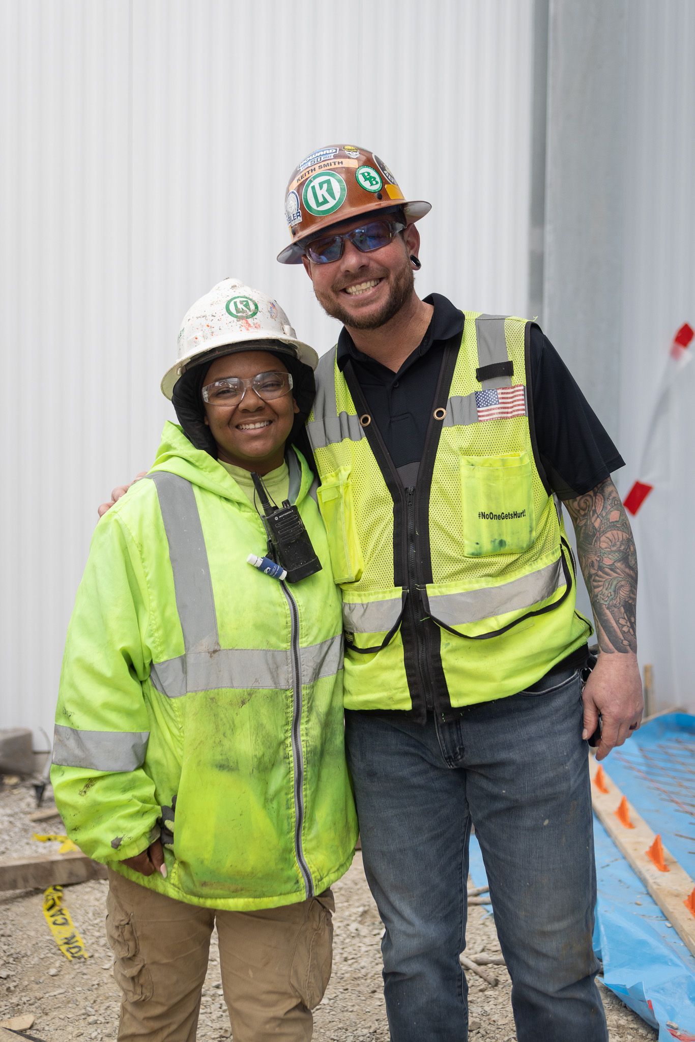 A man and a woman wearing hard hats and safety vests are posing for a picture.