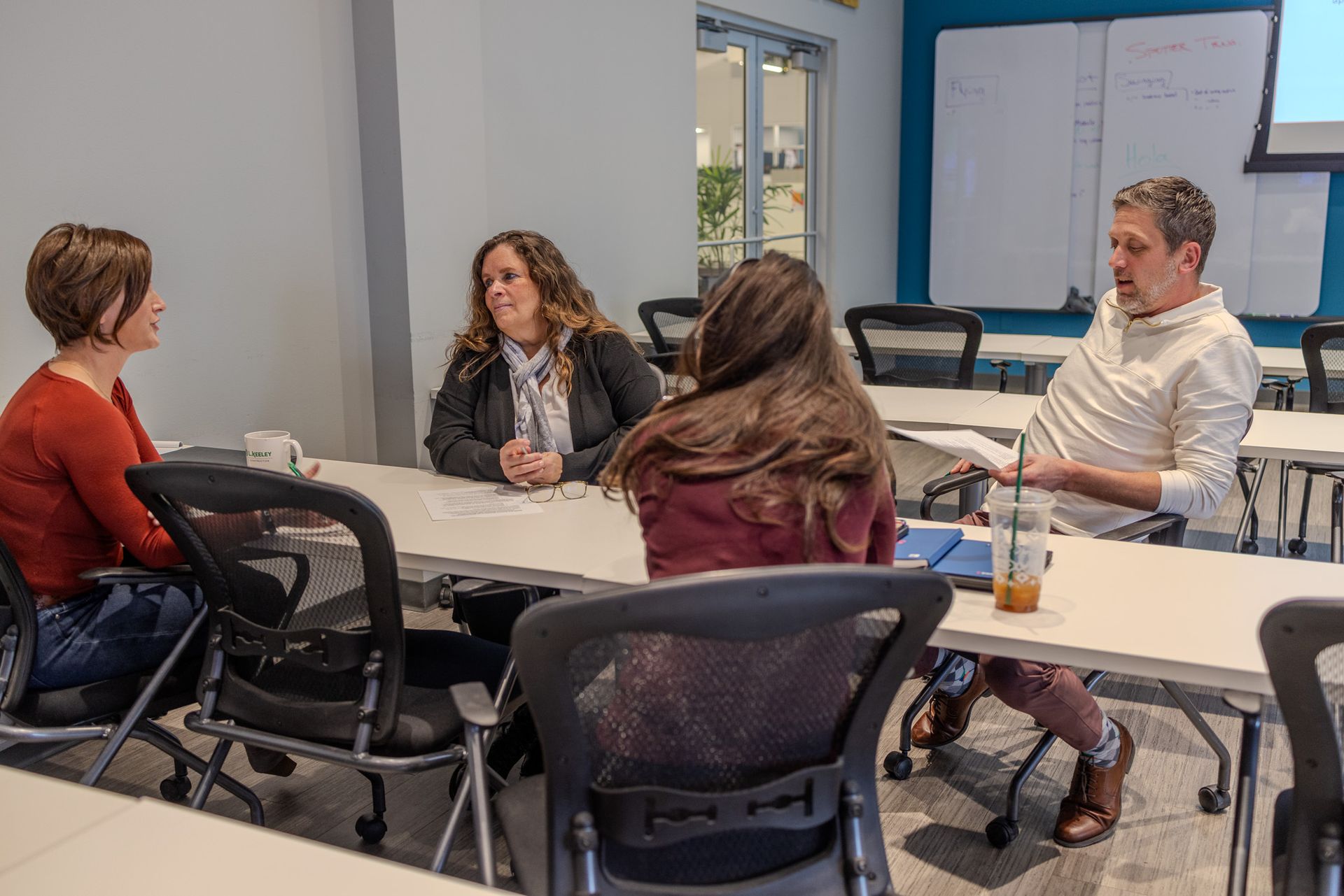 A group of people are sitting at a table in a classroom.