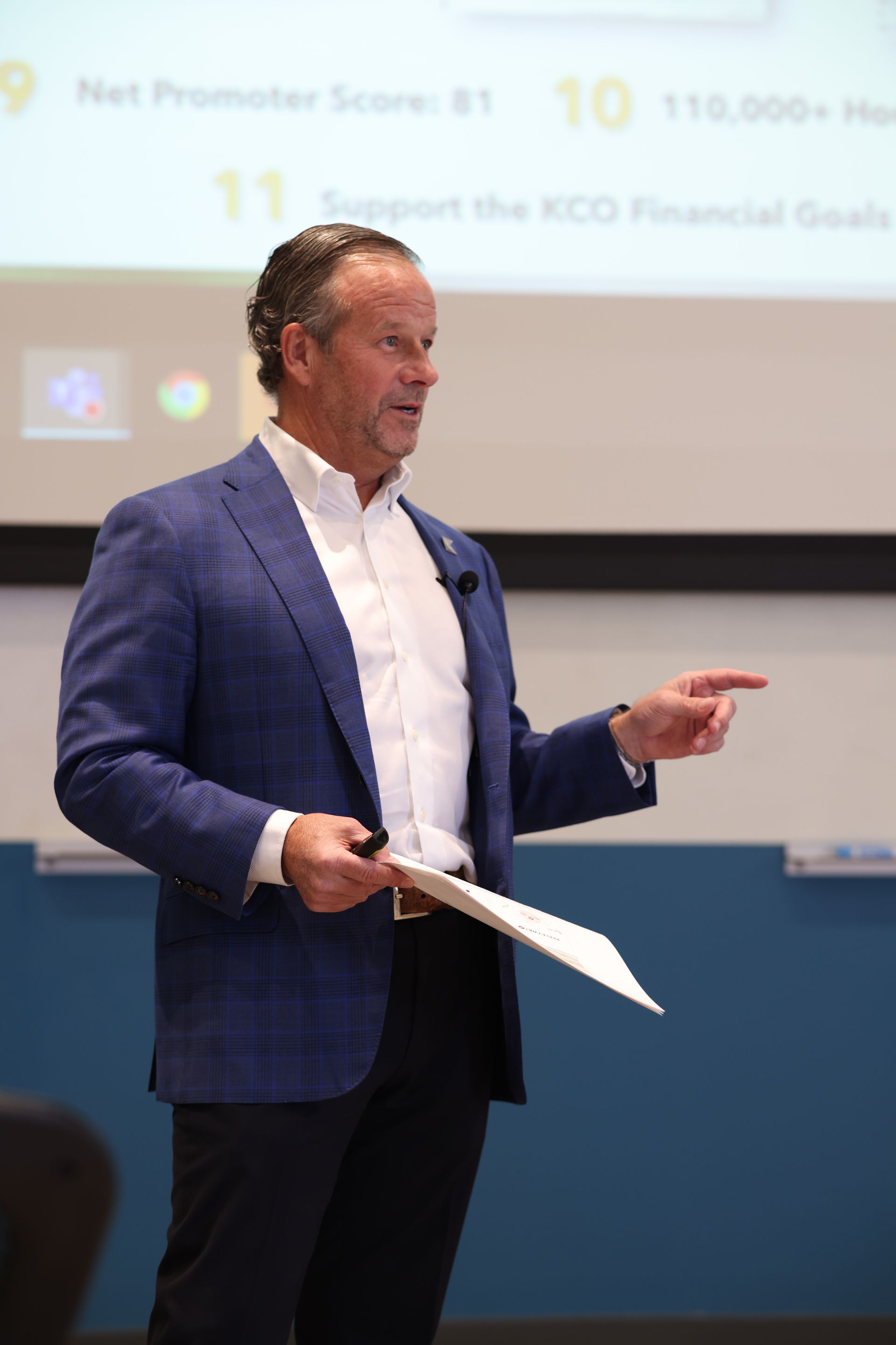 A man in a blue jacket is giving a presentation