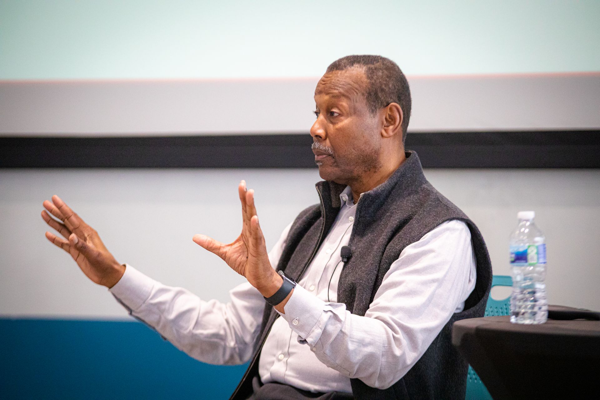 A man is sitting at a table with his hands outstretched.