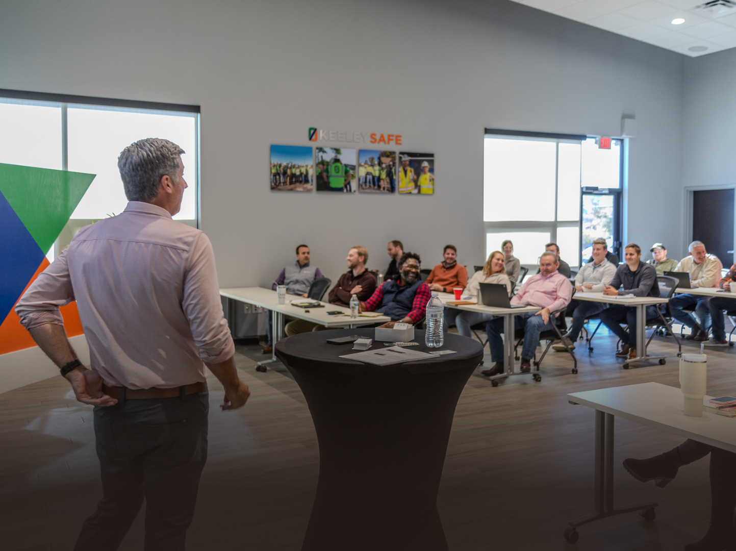 A man is giving a presentation to a group of people sitting at tables in a room.