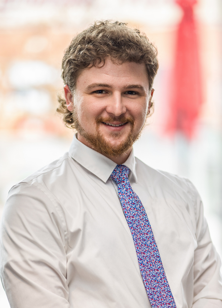 A man in a white shirt and tie is smiling for the camera.