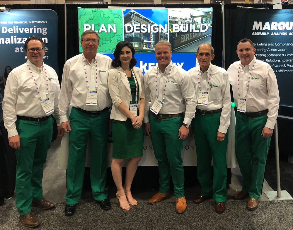 A group of people standing in front of a sign that says plan design build