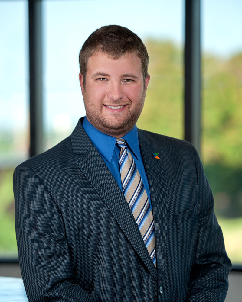 A man in a suit and tie is standing in front of a window.