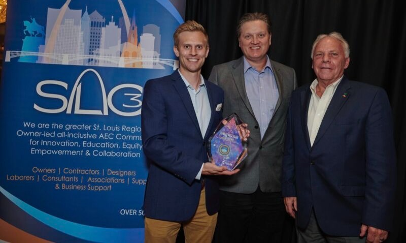 Three men in suits are standing next to each other holding an award.