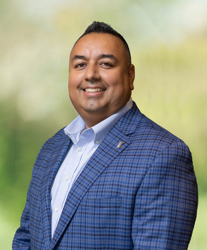 A man in a blue suit and white shirt is smiling for the camera.