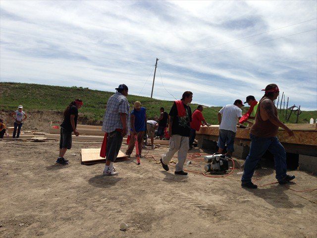 A group of people are working on a construction site at Pine Ridge Reservation