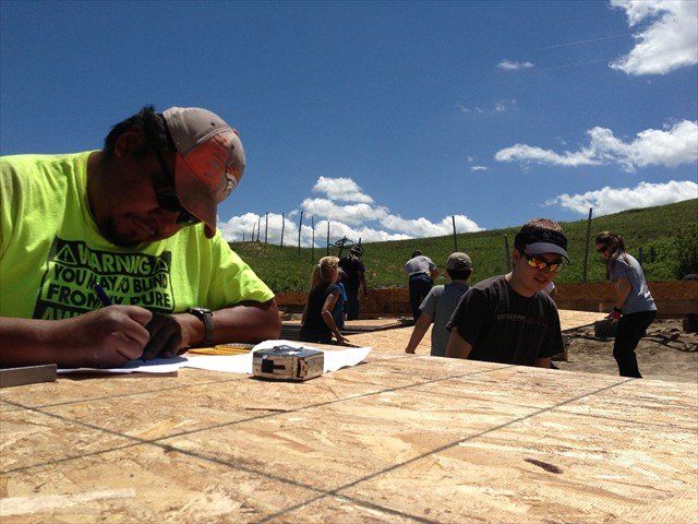 A man in a neon yellow shirt is writing on a piece of paper at Pine Ridge Reservation