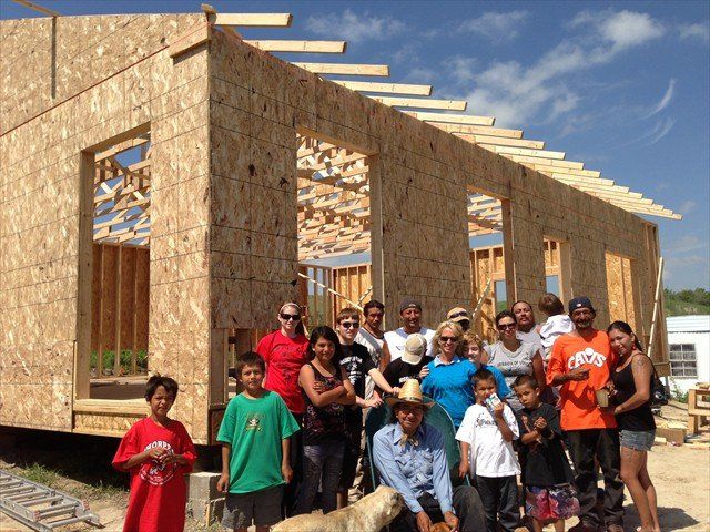 A group of people standing in front of a house under construction at Pine Ridge Reservation