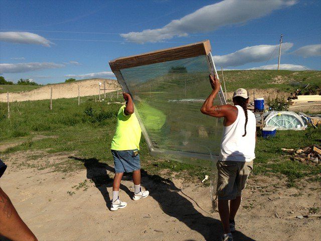 Two men are carrying a large piece of glass at Pine Ridge Reservation