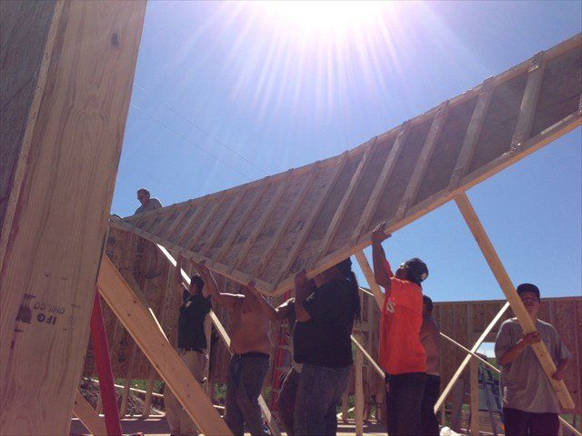 A group of people are working on a wooden structure at Pine Ridge Reservation