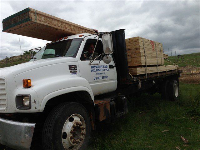 A white truck is carrying a load of wood at Pine Ridge Reservation
