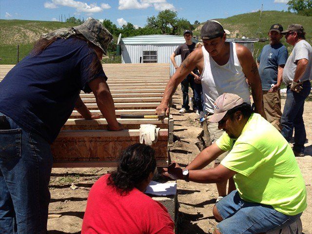 A group of people are working on a wooden structure at Pine Ridge Reservation