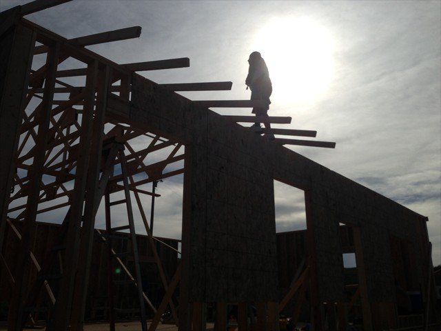 A silhouette of a person standing on top of a building under construction at Pine Ridge Reservation