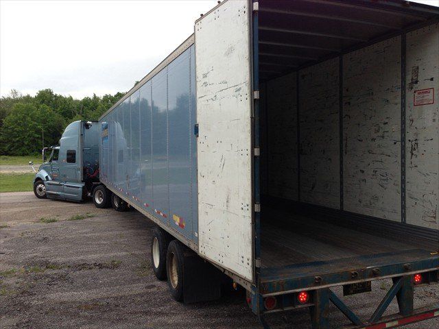 A semi truck at Pine Ridge Reservation parked in a parking lot with its trailer open.