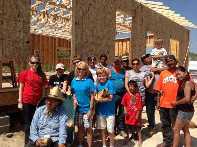 A group of people are posing for a picture in front of a house under construction at Pine Ridge Reservation