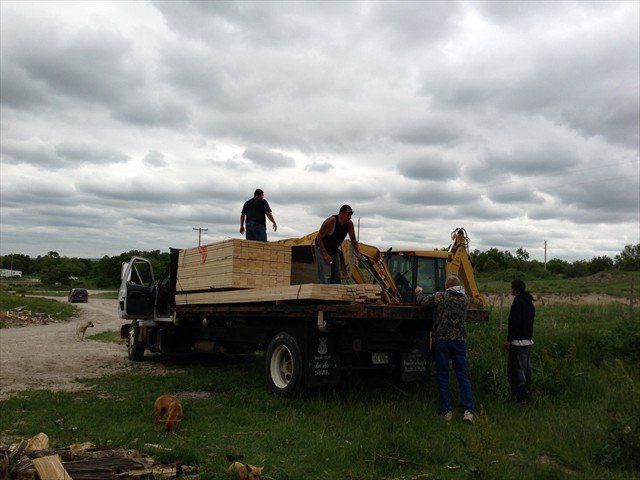A group of men are loading a truck with a wooden box on top of it at Pine Ridge Reservation